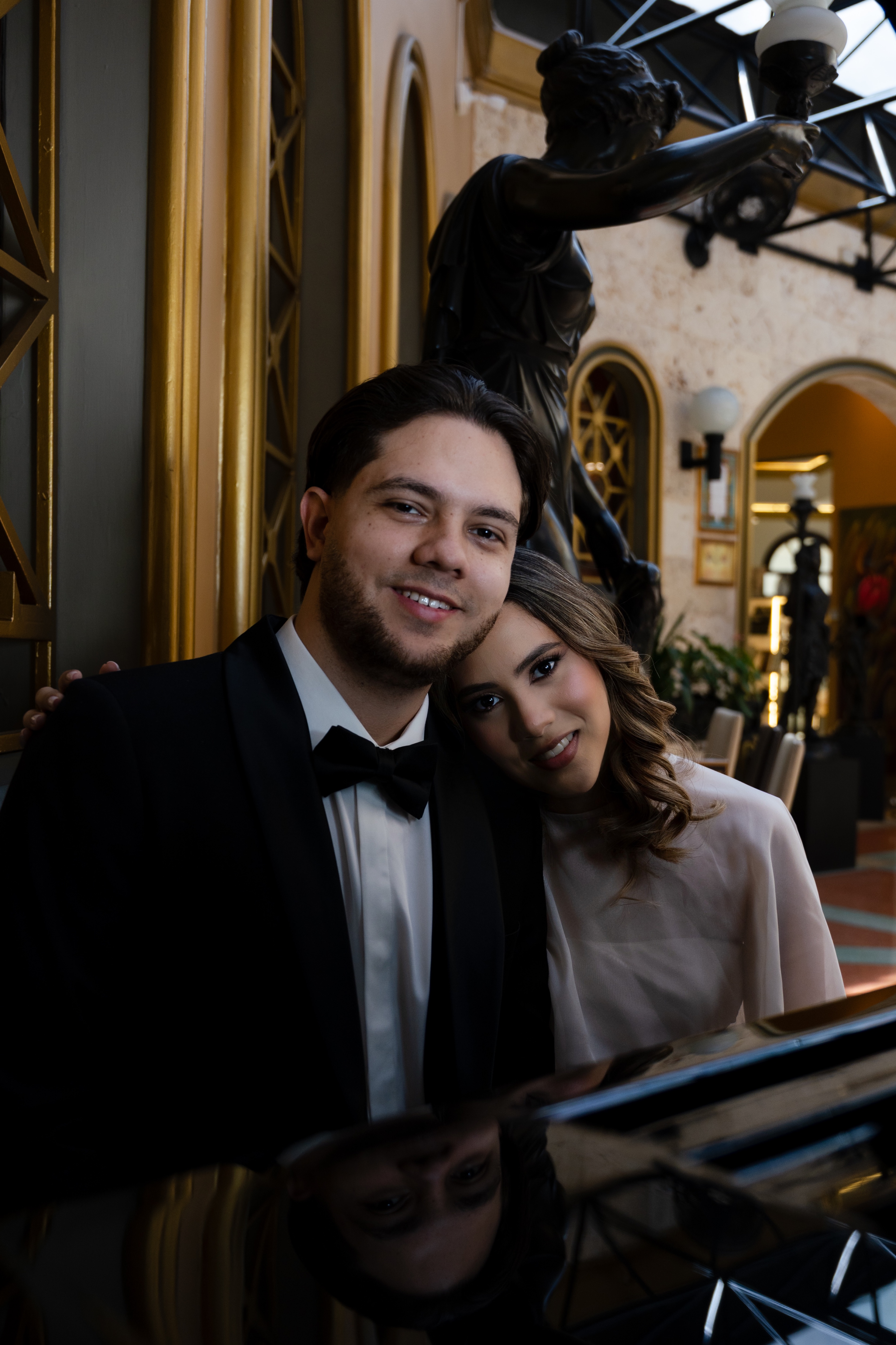 Kristel y Sebastián sonriendo junto a la estatua de bronce